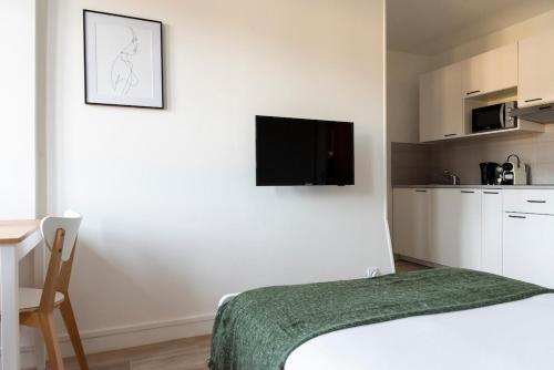une chambre avec un lit et une télévision sur un mur dans l'établissement Studio central et cosy à Caen, à Caen