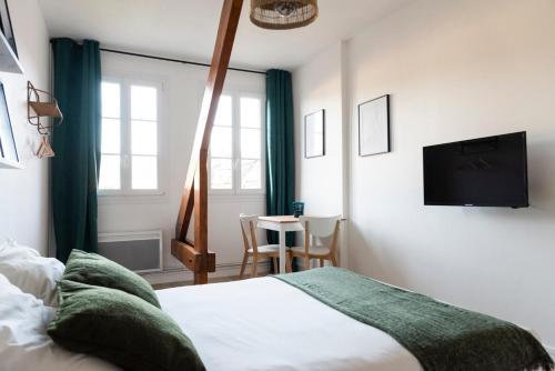 une chambre avec un lit et une télévision à écran plat dans l'établissement Studio central et cosy à Caen, à Caen