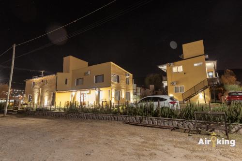 Dos edificios de noche con un coche aparcado delante en Hermosas suites de lujo, en Tafí del Valle