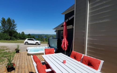 a patio with a bench and a hot tub at Au Sommet du Lac Magog in Magog-Orford