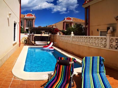 a swimming pool with two chairs next to a house at Chalet Campoamor con piscina privada in Orihuela Costa