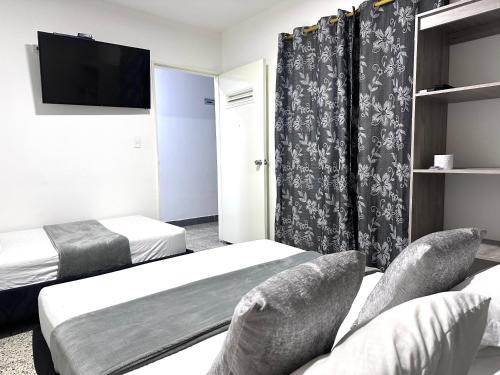 a hotel room with two beds and a flat screen tv at Hotel Guayacanes 70 in Medellín