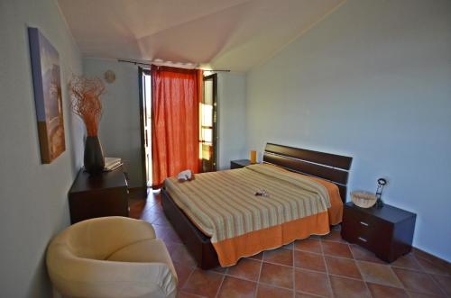 a bedroom with a bed and a chair and a window at Casa Vacanza Arbatax in Àrbatax