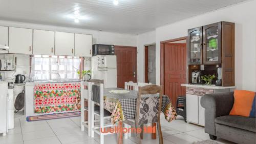 eine Küche mit weißen Schränken, einem Tisch und einer Couch in der Unterkunft Casa em Navegantes próxima a Praia da Miraguaia in Navegantes