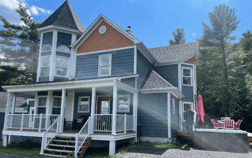 a blue house with a white porch and a porch at Au Sommet du Lac Magog in Magog-Orford