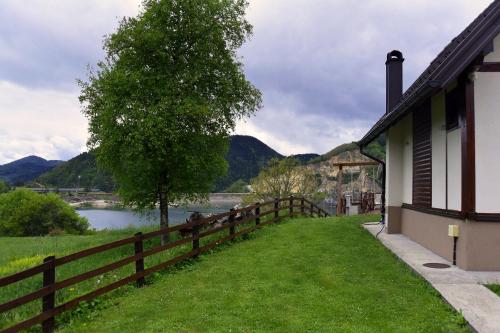 a house with a fence next to a lake at Zoranovi konaci in Jevtići