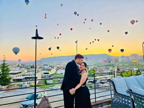 a man and woman standing on a balcony with hot air balloons at Gala Cave Cappadocia in Goreme