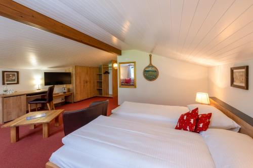 a hotel room with two beds and a desk at Derby Swiss Quality Hotel in Grindelwald