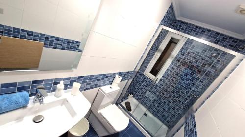 a blue tiled bathroom with a toilet and a sink at Apartamento Playa Catedrales & Piscina I in San Pedro de Benquerencia