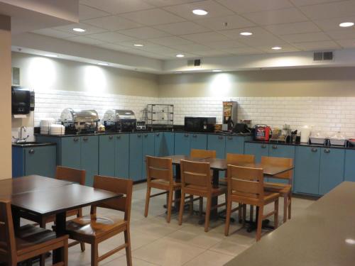 a kitchen with blue cabinets and wooden tables and chairs at Country Inn & Suites by Radisson, Camp Springs Andrews Air Force Base , MD in Camp Springs