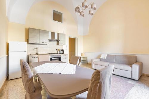 a kitchen and living room with a table and a couch at Dimora Le Tre Muse Guesthouse in Lecce