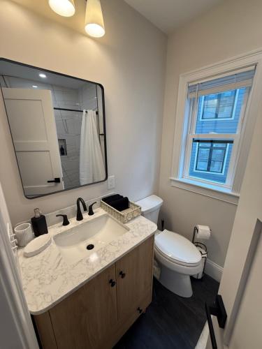 a bathroom with a sink and a toilet and a mirror at Boston First floor condo in Framingham