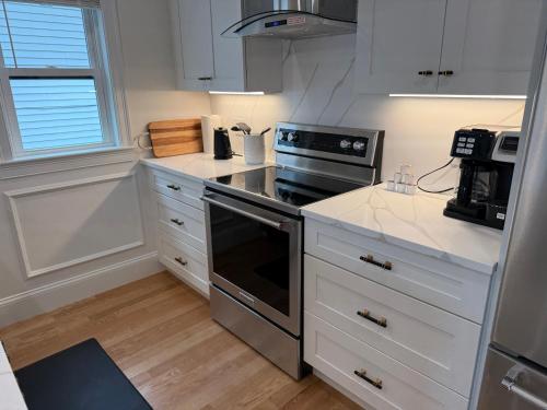 a kitchen with white cabinets and a stove top oven at Boston First floor condo in Framingham