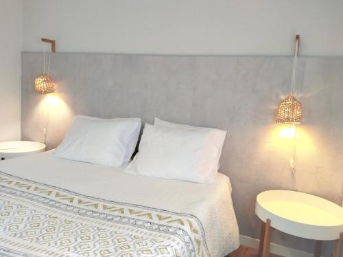 ein Schlafzimmer mit einem Bett mit weißen Kissen und zwei Lichtern in der Unterkunft Casa de São Roque Açores in Ponta Delgada