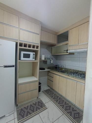 a kitchen with a refrigerator and a microwave at Confortável Apto de 2 Quartos - Lagoa Quente in Caldas Novas