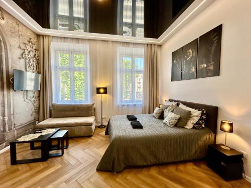 a bedroom with a bed and a couch and windows at Sky Mirror jacuzzi in Krakow