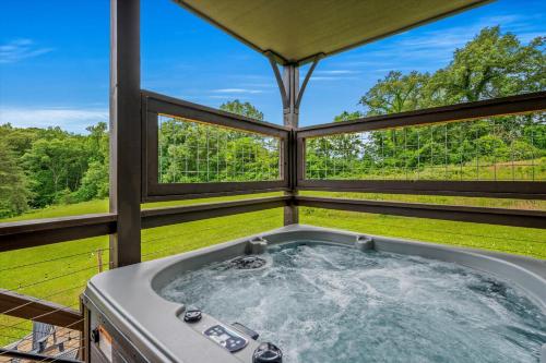 a jacuzzi tub in a porch with windows at Smoky Oasis, Hot Tub, Luxury Sauna, Fire Pit, Arcade Games, Free Pets in Sevierville