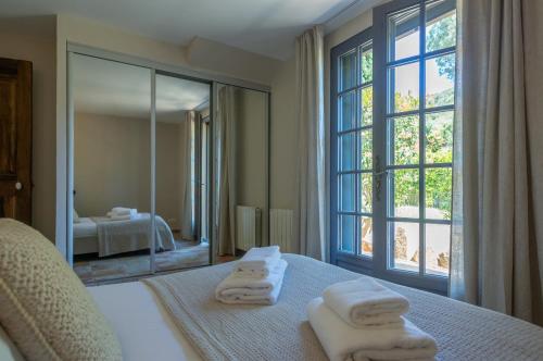 - une chambre avec des serviettes sur un lit et un grand miroir dans l'établissement Villa Vallée Longa - Tarra Zuria, à Bonifacio