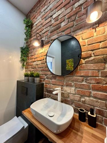 a bathroom with a white sink and a brick wall at Sky Mirror jacuzzi in Krakow