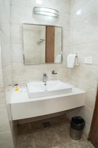 a bathroom with a white sink and a mirror at Grand Hridey 1 minute from Railway Station in Amritsar