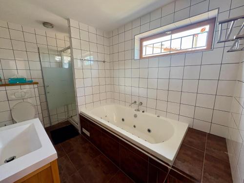 un bagno piastrellato bianco con vasca e lavandino di Maison avec piscine VIVES 8 couchages 4 chambres a Vivès