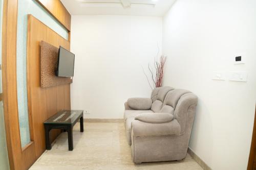 a living room with a chair and a tv at Grand Hridey 1 minute from Railway Station in Amritsar
