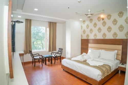 a bedroom with a bed and a table and chairs at Grand Hridey 1 minute from Railway Station in Amritsar