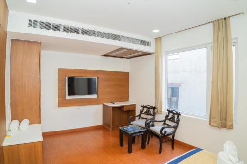 a living room with two chairs and a tv at Grand Hridey 1 minute from Railway Station in Amritsar