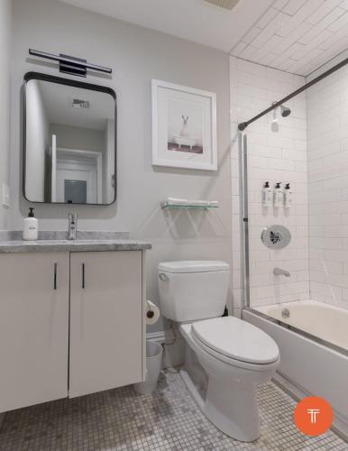 a white bathroom with a toilet and a sink and a tub at 304 Newbury Street by Thatch in Boston