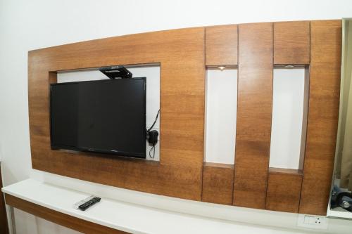 a flat screen tv on a wall with three mirrors at Grand Hridey 1 minute from Railway Station in Amritsar