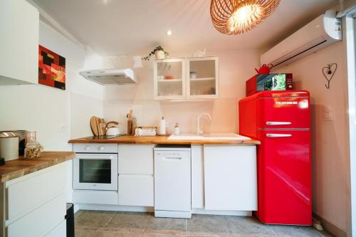 a red refrigerator in a kitchen with white cabinets at Charmant 2 pièces proche centre ville et mer in Saint-Raphaël