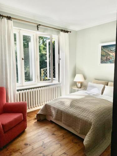 a bedroom with a bed and a chair and windows at Zabytkowy dom w Podkowie Leśnej in Podkowa Leśna