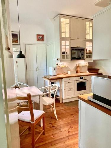 a kitchen with white cabinets and a table and chairs at Zabytkowy dom w Podkowie Leśnej in Podkowa Leśna