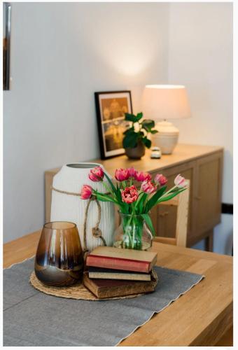 a table with books and a vase of flowers and a candle at Stadthaus im Altstadtkern für bis zu 8 Personen in Dingolfing