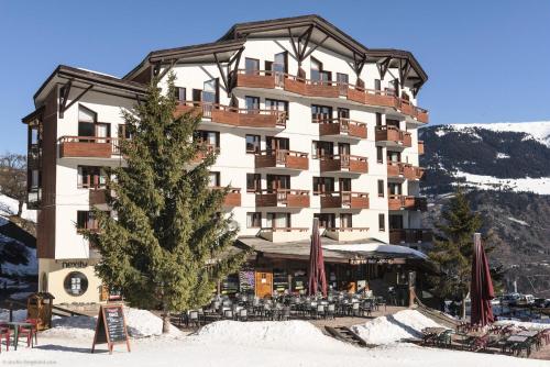 un grande edificio con un albero nella neve di Résidence Le Britania - maeva Home - Appartement 2 pièces 4 personnes - Sélection MAE-6673 a La Tania