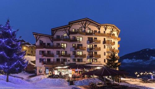 un grand bâtiment avec un arbre de Noël en face dans l'établissement Résidence Le Britania - maeva Home - Appartement 2 pièces 4 personnes - Sélection MAE-6673, à La Tania