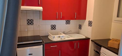 - une cuisine avec des placards rouges et un évier blanc dans l'établissement studio la rochelle, à La Rochelle