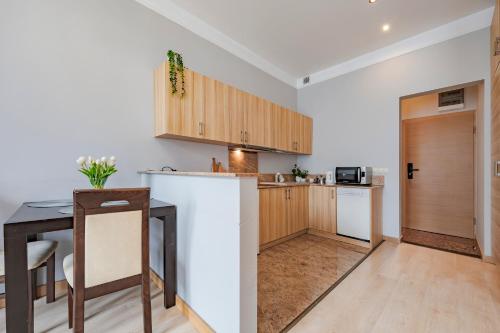 a kitchen with wooden cabinets and a table and a counter at Amber Apartments in Gdańsk