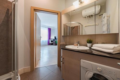 a bathroom with a sink and a washing machine at Amber Apartments in Gdańsk