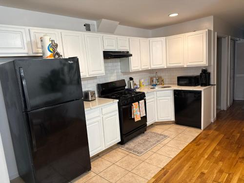 a kitchen with white cabinets and a black refrigerator at Urban beautiful home Jersey City 15 mins from NYC 15 mins from Newark airport in Jersey City