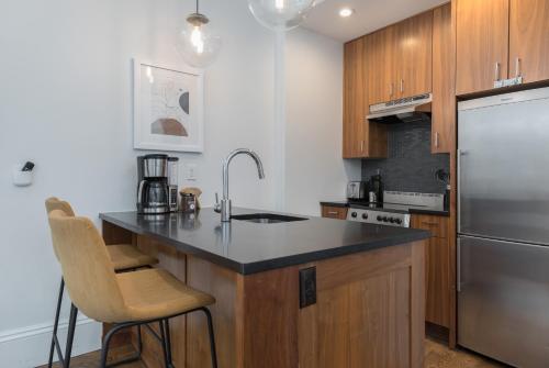 a kitchen with a stainless steel refrigerator and wooden cabinets at 304 Newbury Street by Thatch in Boston