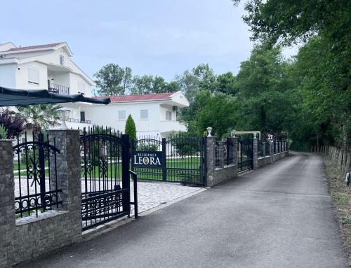 a fence in front of a house with a driveway at Residence LEORA in Ulcinj