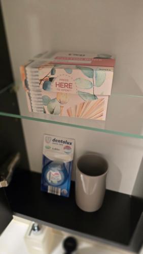 a shelf above a sink with a cup and books at BlueLoft Kaunas in Kaunas