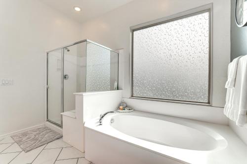 a white bathroom with a tub and a shower at Swim-Up Bar and Putting Green Goodyear Getaway! in Goodyear