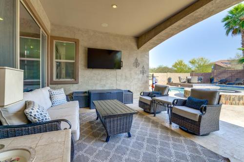 a patio with couches and a table and a tv at Swim-Up Bar and Putting Green Goodyear Getaway! in Goodyear