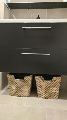a black bathroom sink with two baskets under it at BlueLoft Kaunas in Kaunas