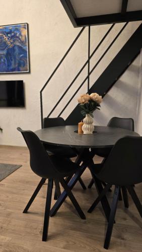 a black table with chairs and a vase of flowers on it at BlueLoft Kaunas in Kaunas