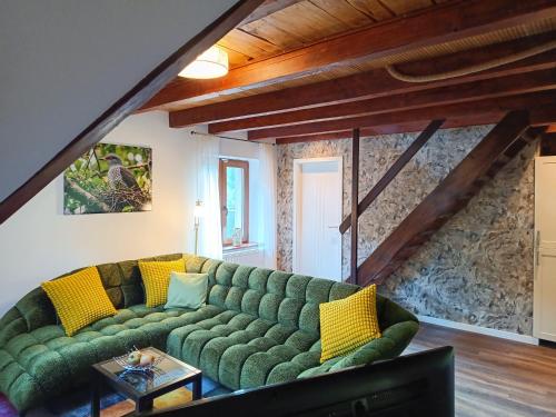 a living room with a green couch with yellow pillows at Kuckucksnest - Nid de Coucou in Sondernach
