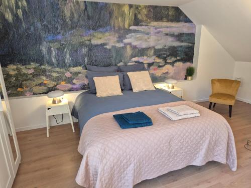 a bedroom with a bed with a painting on the wall at Maison Floréal Giverny in Giverny