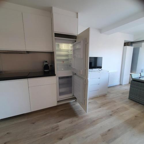 une cuisine vide avec des armoires blanches et une télévision dans l'établissement Studio aux pieds de la Marina avec wifi et clim, à Canet